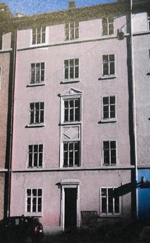 3 story building, pink walls, multiple windows, centered door