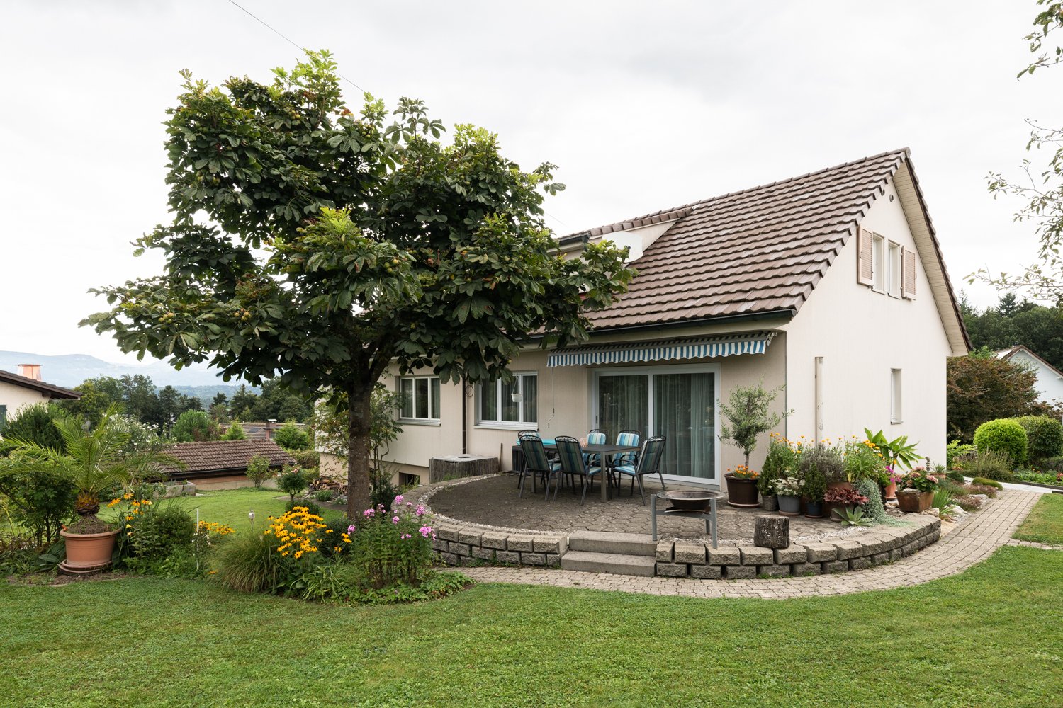 Detached house, brown roof, large tree, large garden, outdoor dining table, brick pathway
