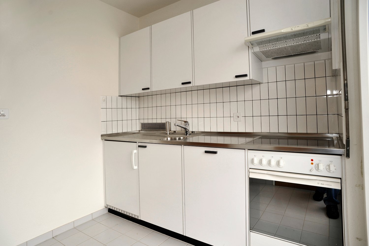 modern kitchen with white cabinets, stainless steel countertop, gas stove, oven, and sink with faucet