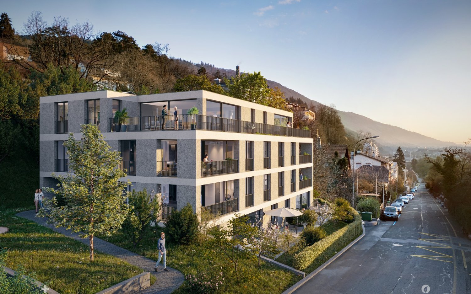A modern, multi-story apartment building with balconies, surrounded by greenery and situated on a hillside overlooking a road and scenic mountain landscape.