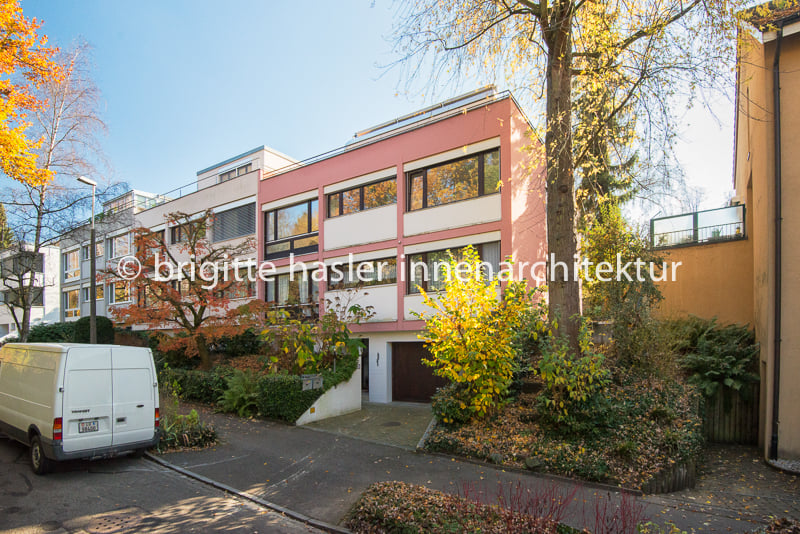 3 story building, pink and white exterior, garage, trees, plants, street light