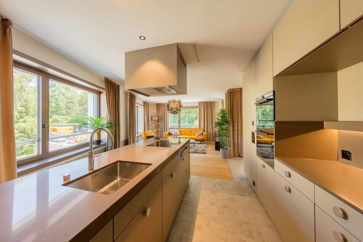 Spacious open-concept kitchen with modern appliances, including a dishwasher, large windows overlooking the outdoor scenery, and a dining area with yellow accents in the living room