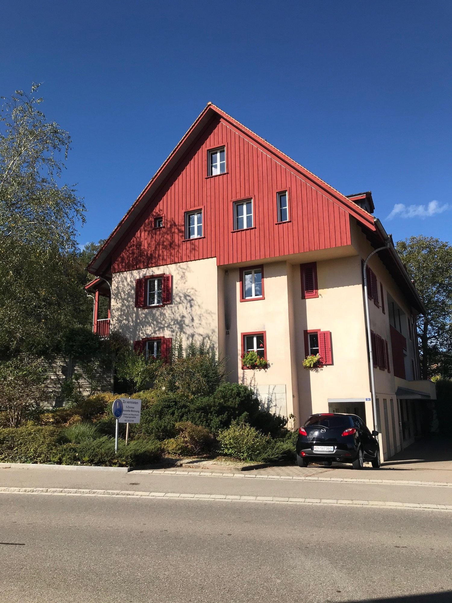 2 story house, red roof, white and red shutters, balcony, car parked in front