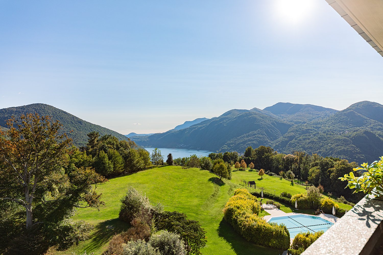 vast grass field, swimming pool, trees, lake view, clear sky