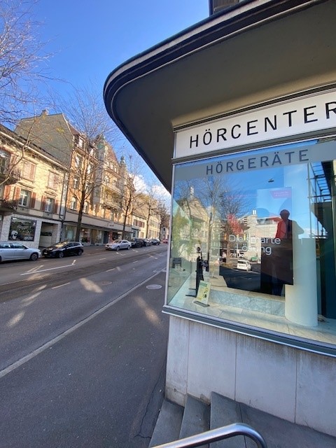 Storefront of Horcenter Horgerate, glass storefront, entrance steps, cars parked on the street