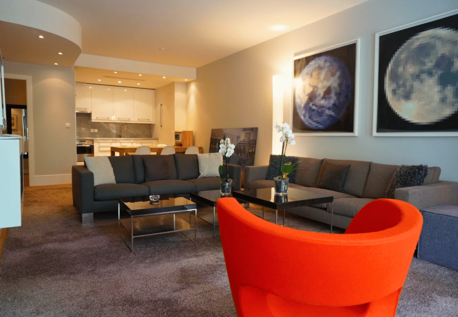 modern living room, with gray sofa, orange chair, glass tables, and flower vases