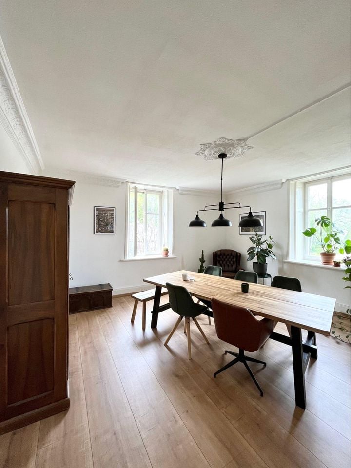 long dining table, white wooden bench, modern chairs, vintage cabinet, white walls, picture frames, ceiling lamp, large windows, wooden floor