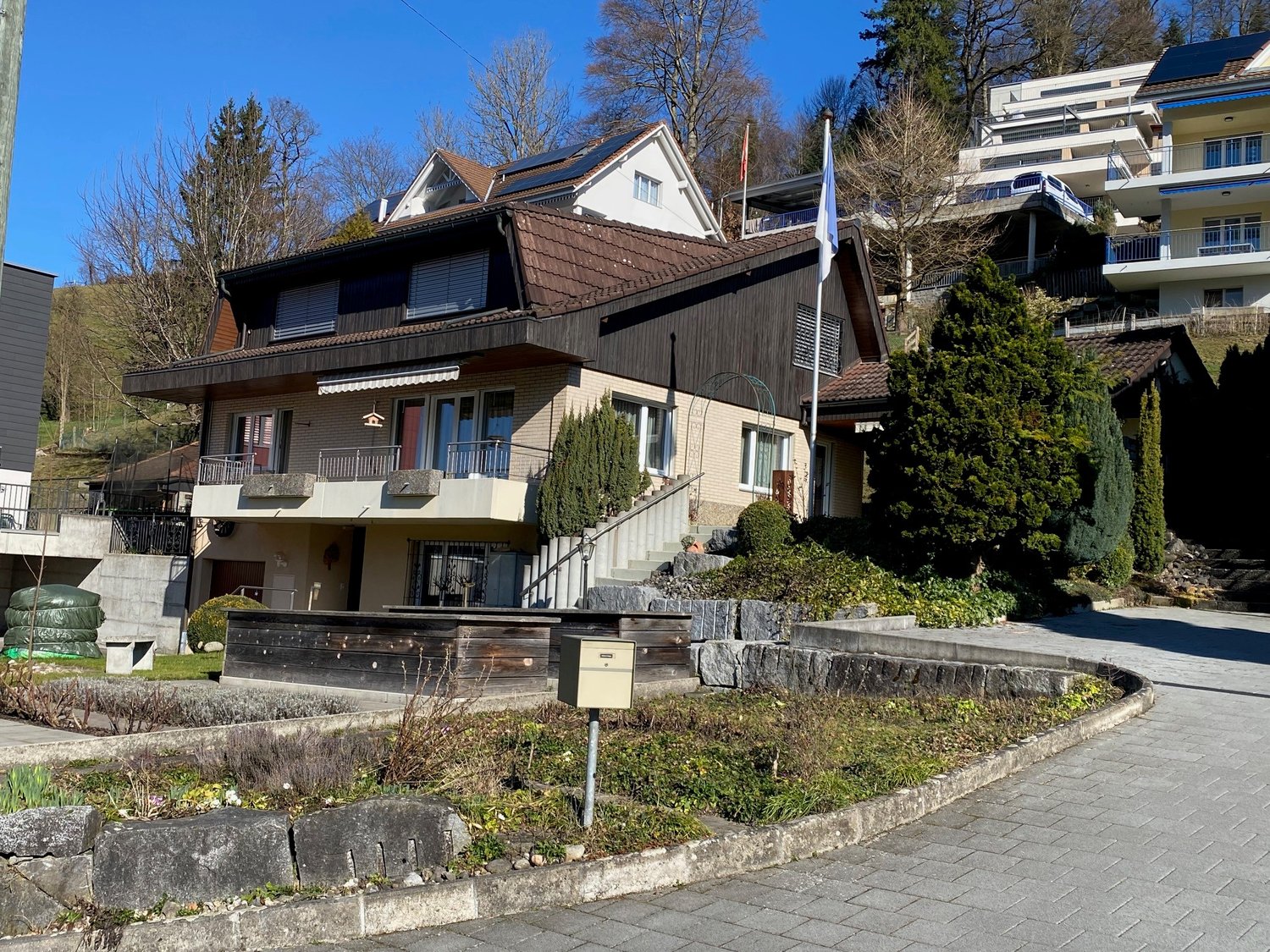 3-story house, brown roof, beige facade, several balconies, staircases