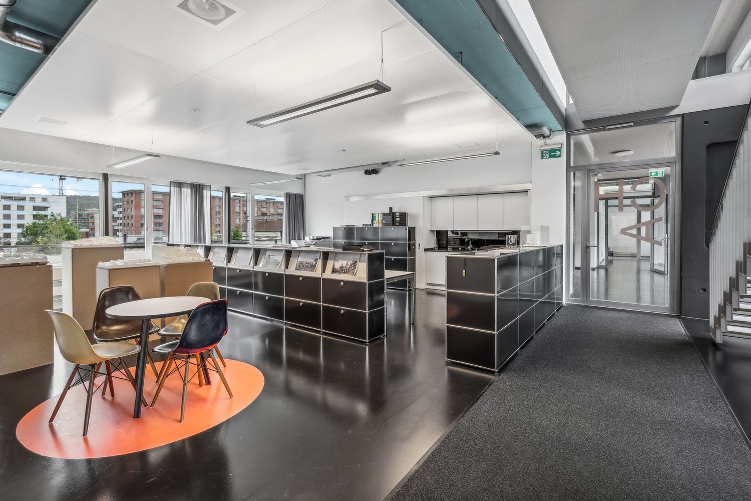 modern office space with high ceilings, white walls, large windows, black flooring, modern furnishings