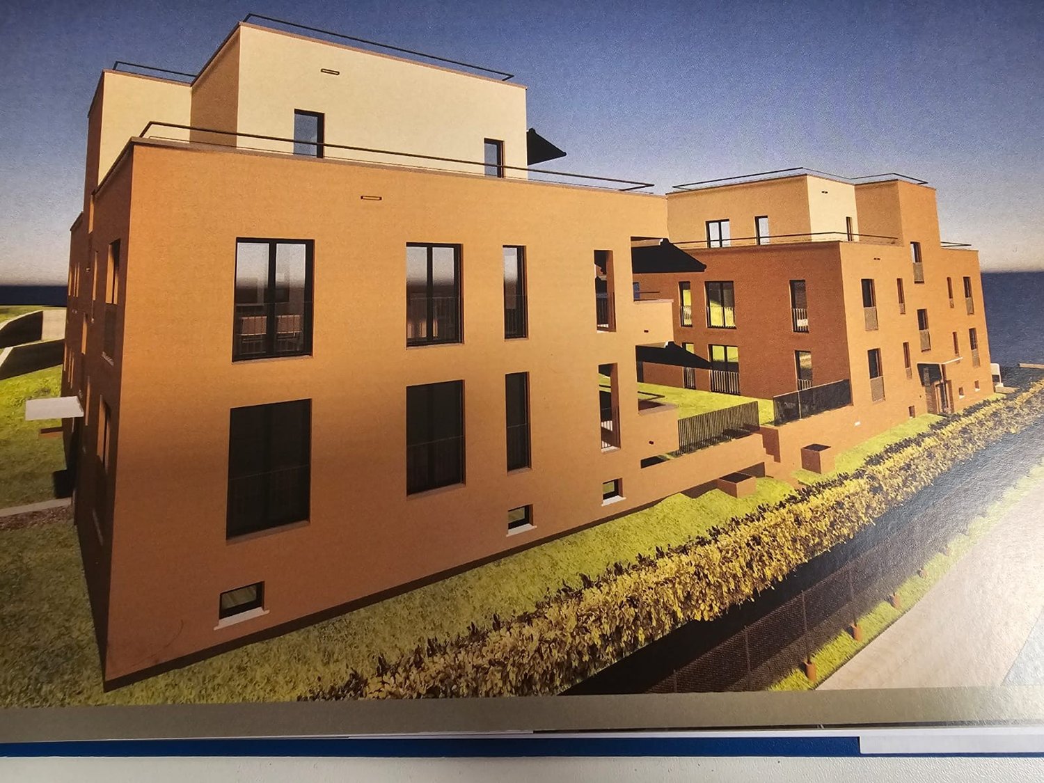 Brown building with multiple floors, modern architecture, glass windows, terraces on top, small garden in front.