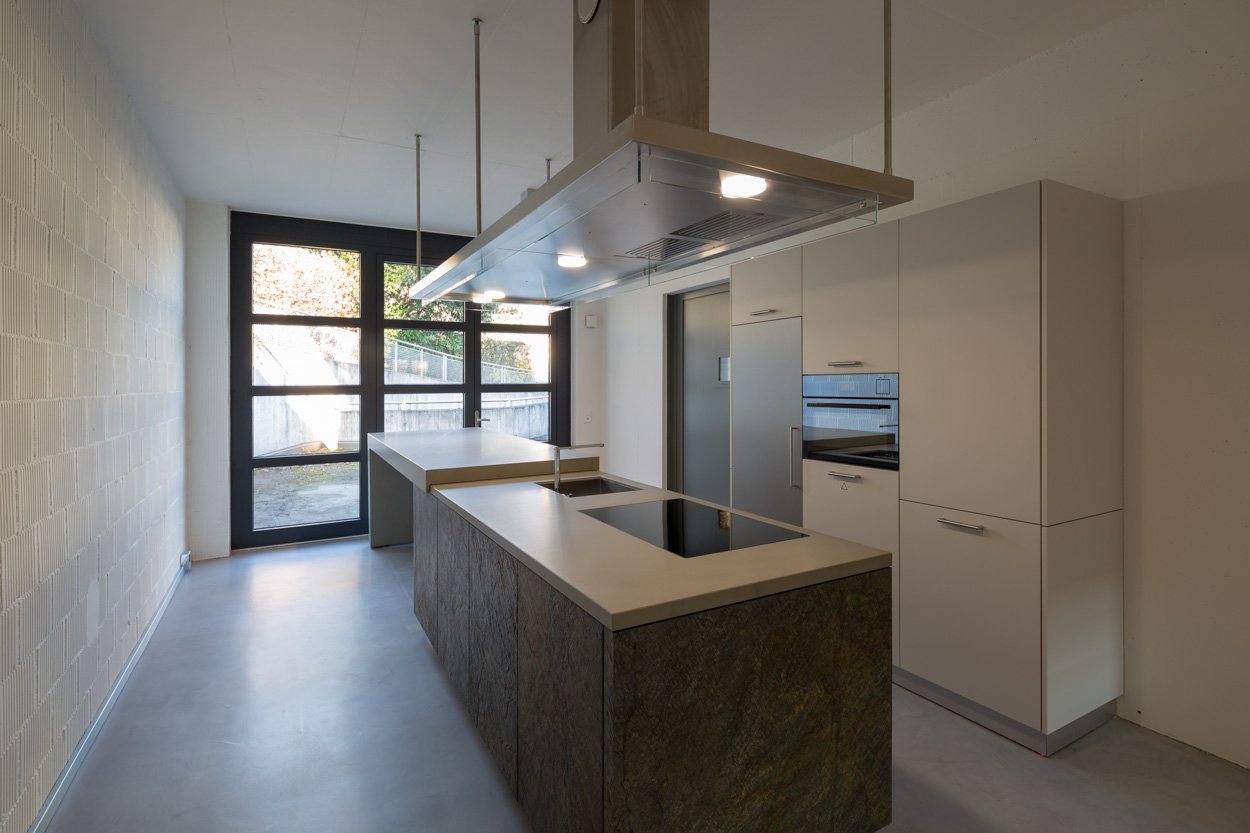 modern kitchen with island, two sinks, induction cooktop, oven, extractor hood, white cabinets, tiled floor
