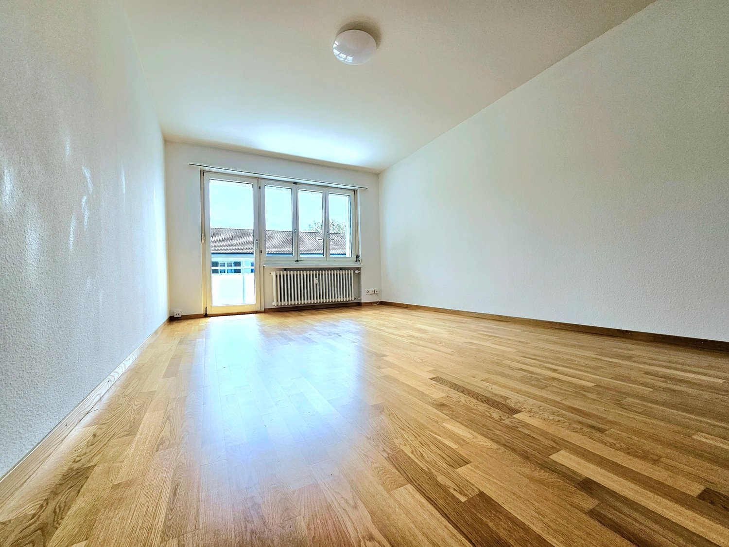 empty room, hardwood floors, white walls, large windows, white ceiling, white radiator