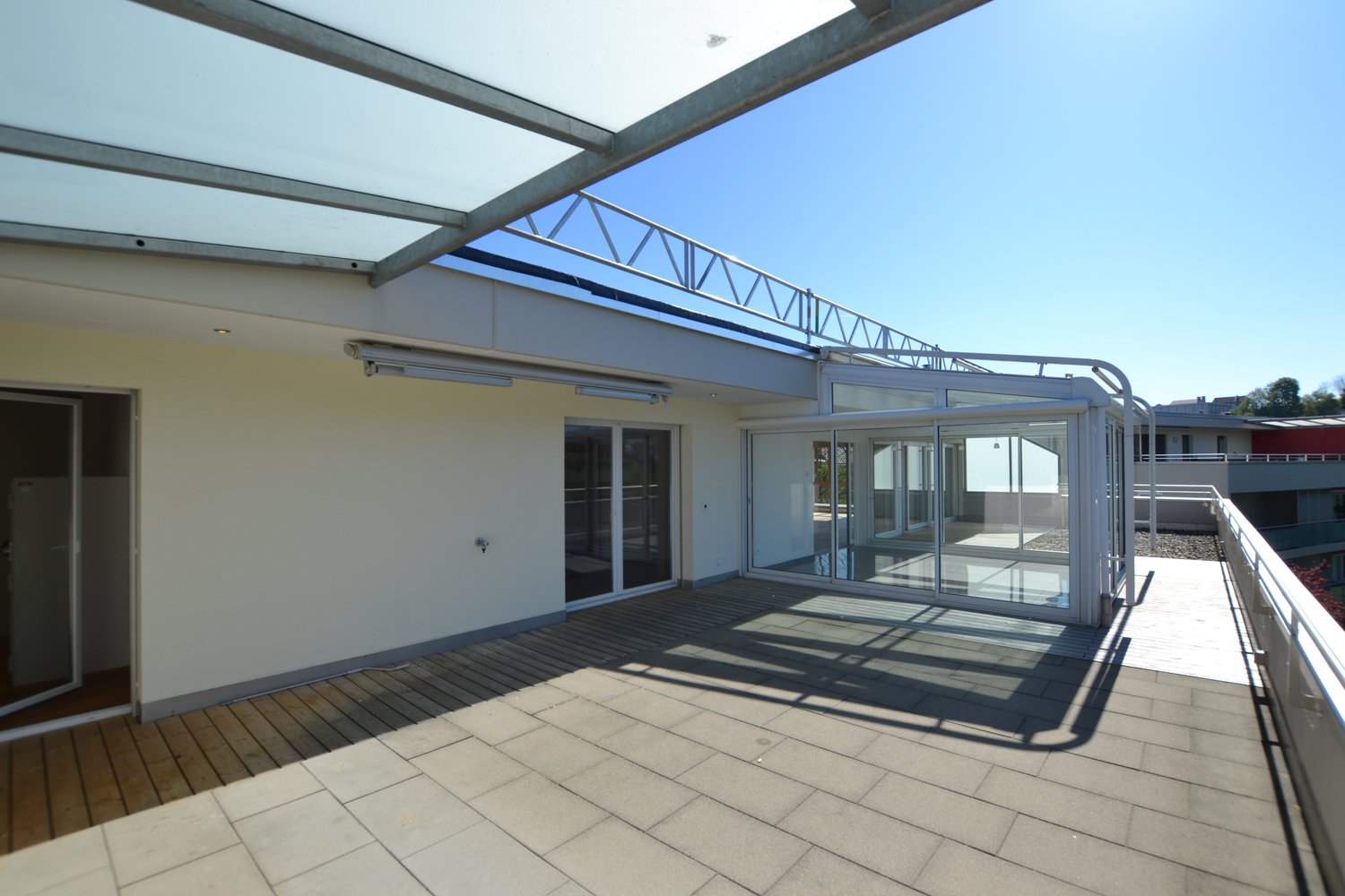covered balcony with wooden floor, glass walls, metal railings