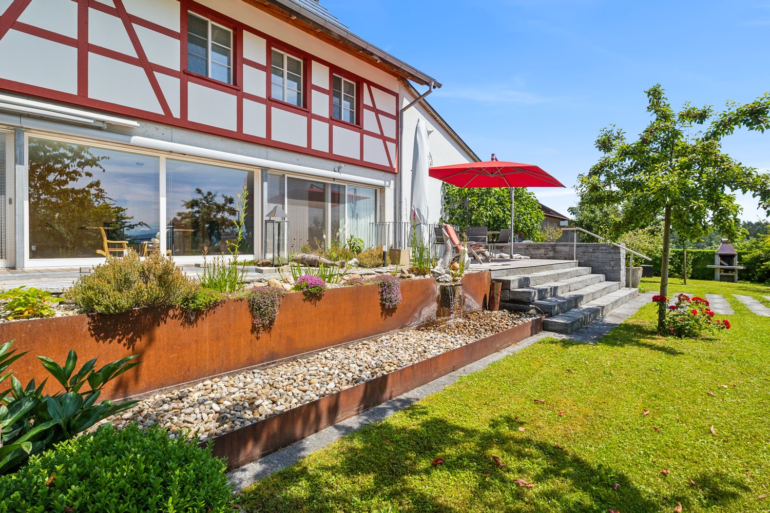 white and red exterior, large glass windows, red umbrella, red brick stairway, landscaped garden