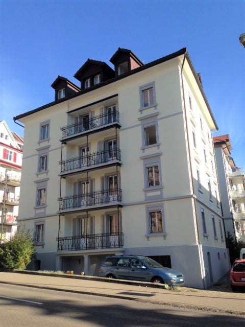 Apartment building, multiple floors, balconies, parked cars