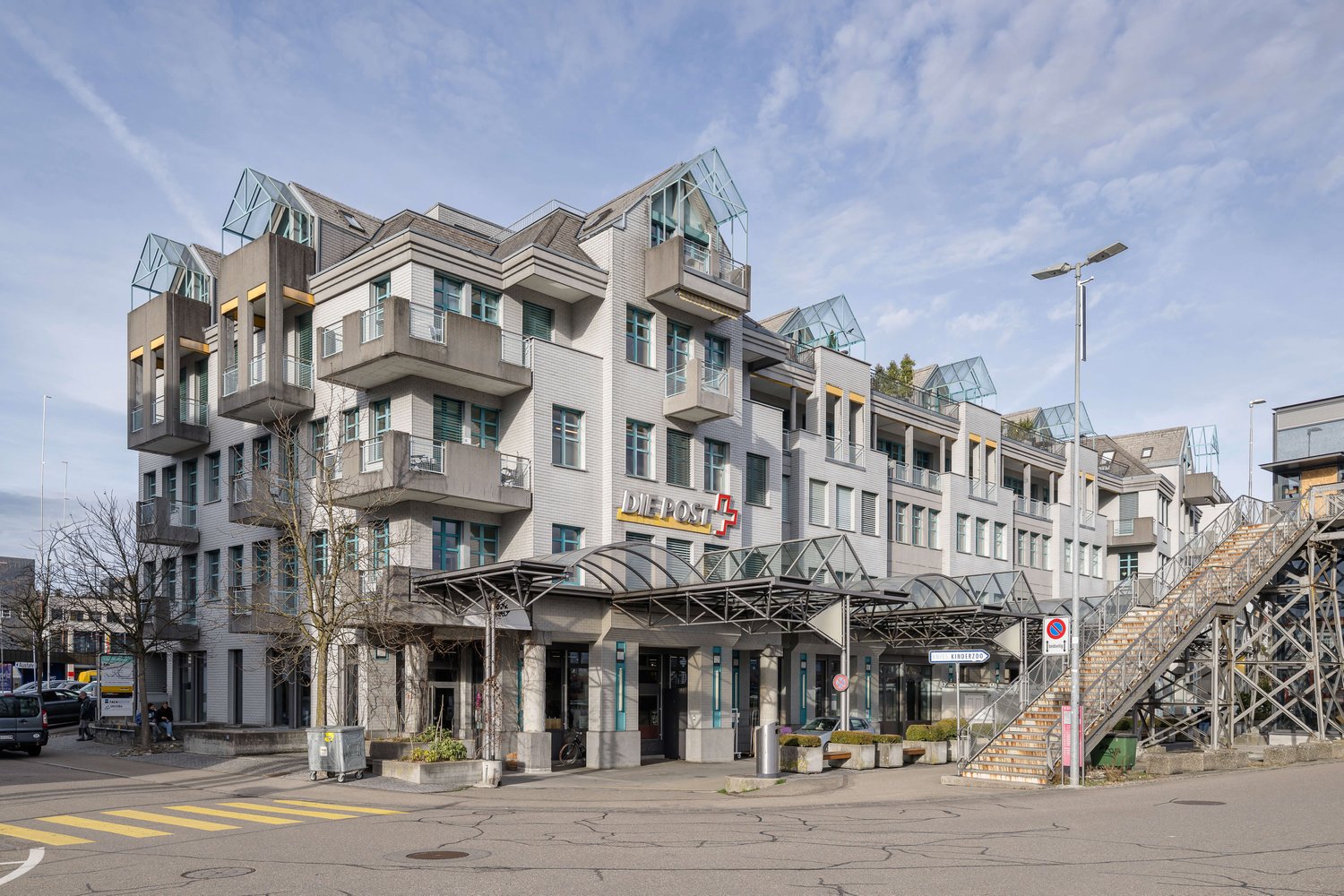 multistory residential building, many balconies, glass entrance canopy, sign reading Die Post