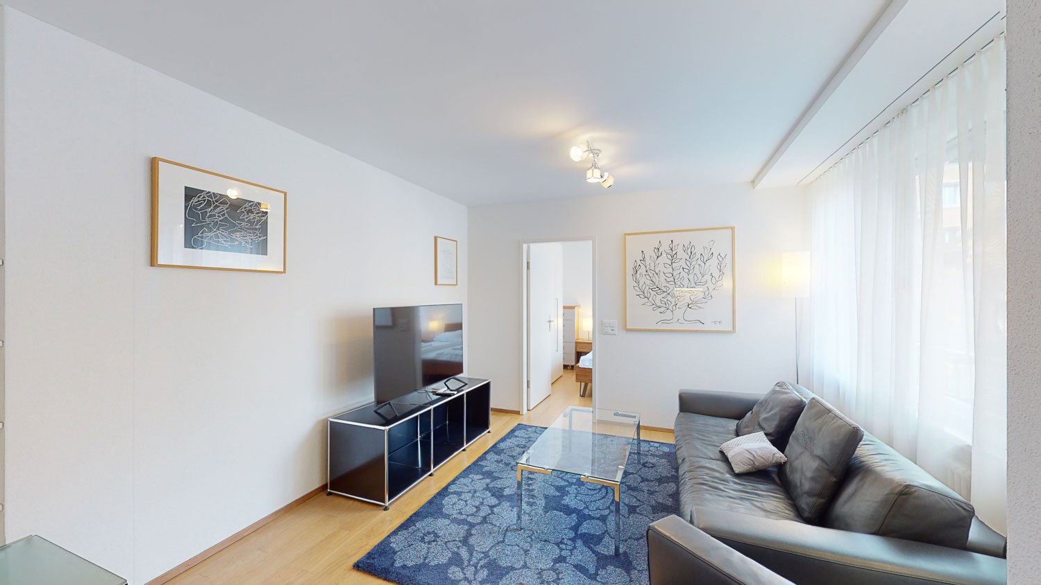 living room with TV, couch, coffee table, rug, artwork, open door to bedroom, sliding glass doors