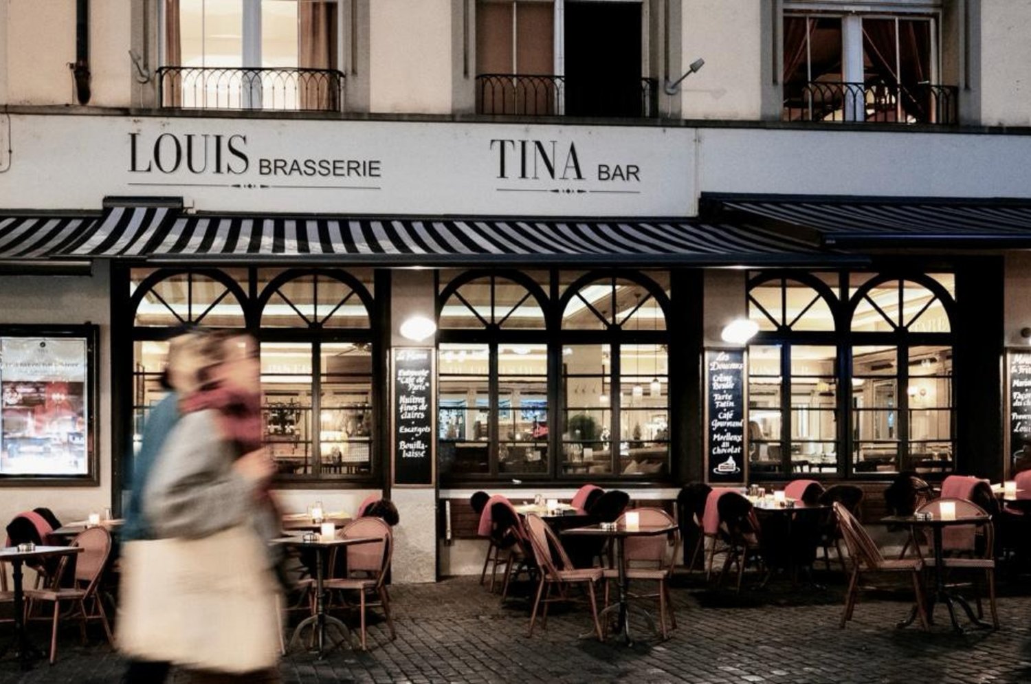 brasserie with arched windows, outdoor seating, black and white awning