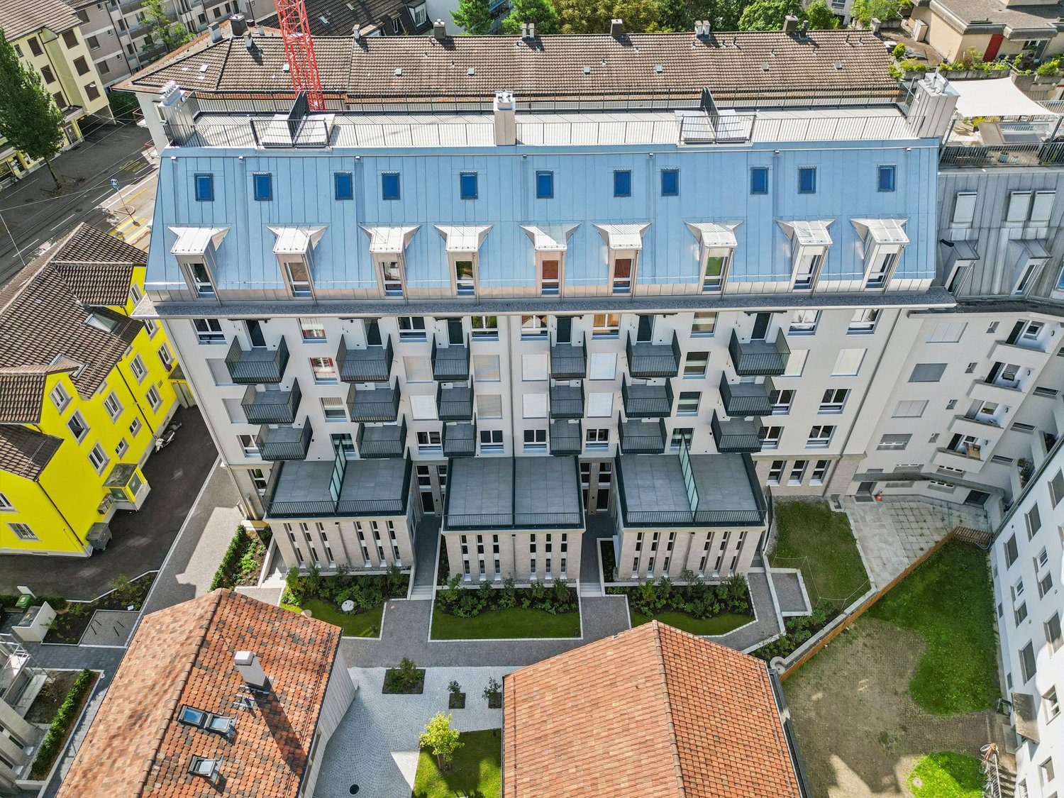 modern residential building, multiple balconies, large glass windows, landscaped area