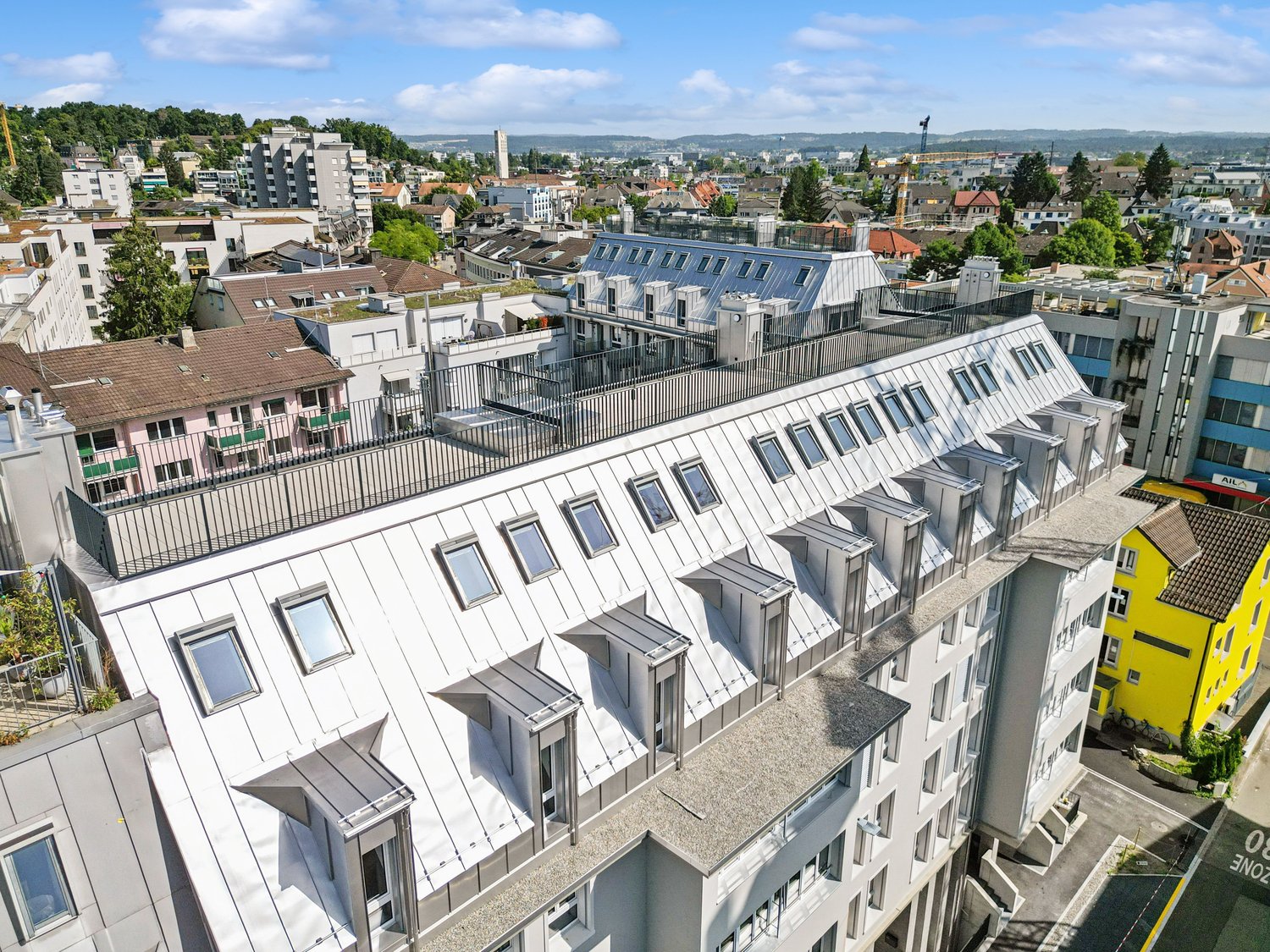 multiple story building with a terrace, windows, chimneys, a sloped roof, balconies, and city view