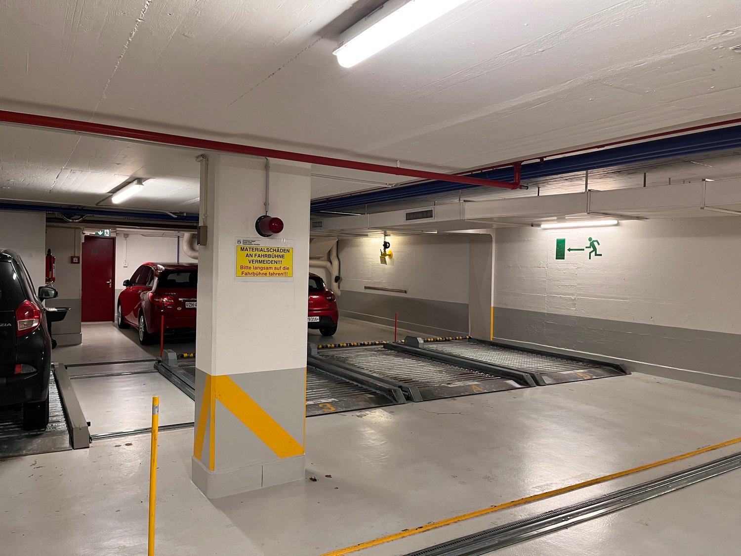 underground parking with parking spots, safety lights, and yellow and red warning stripes