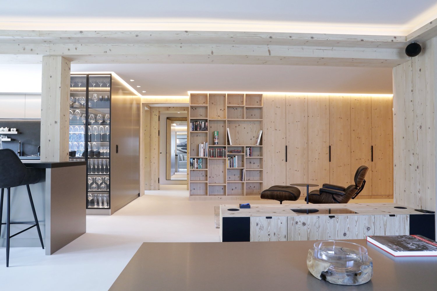 living room with wooden features, modern design, open shelves, armchairs, coffee table, books