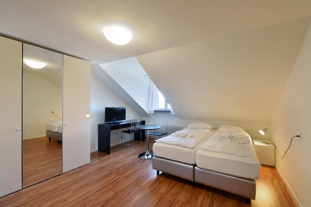 Double bedroom with two beds, television, table, chairs, closets, and ceiling lamp