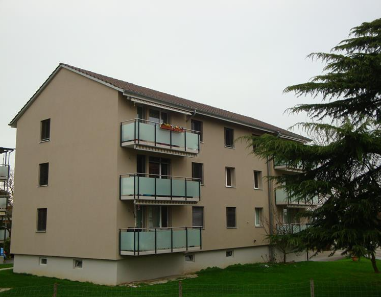 3 story apartment building, beige exterior, multiple balconies, green lawn, trees