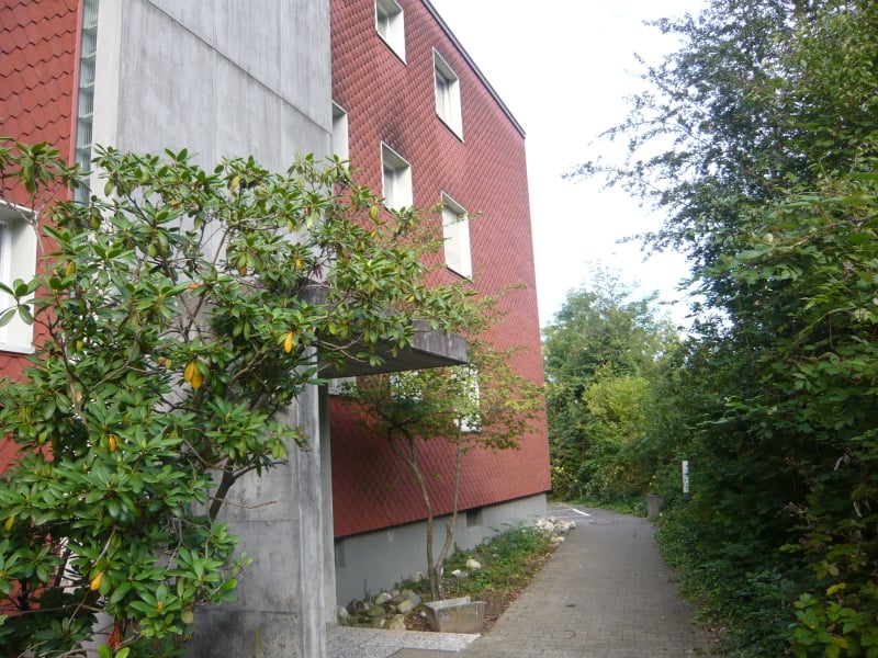 The building has a red facade with windows, and a balcony/terrace.