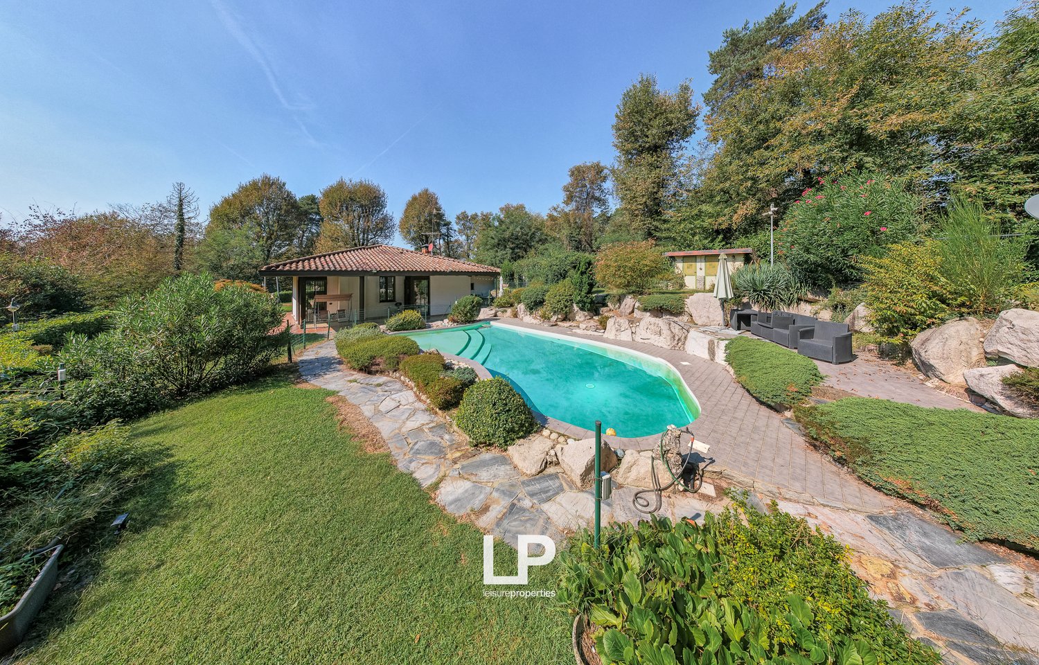 House with swimming pool, red tiled roof, garden, paved path, sitting area with chairs