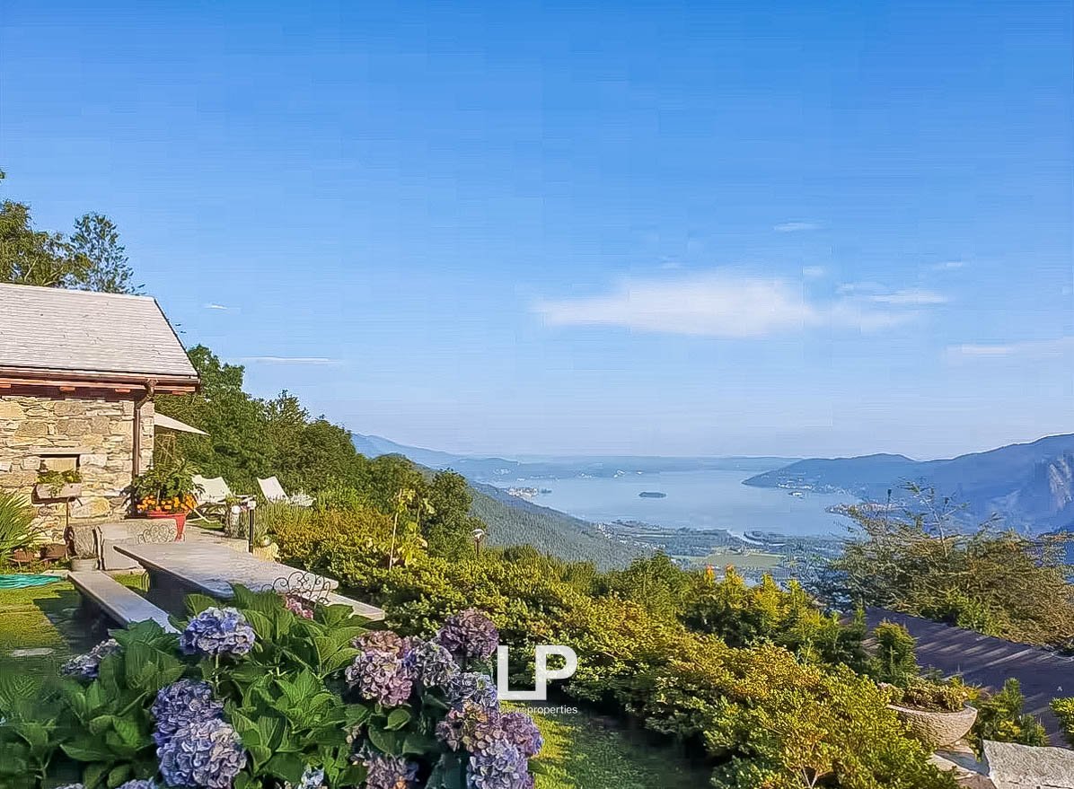 astonishing views of the mountains and the sea, beautiful landscaping, two white chairs, and potted plants