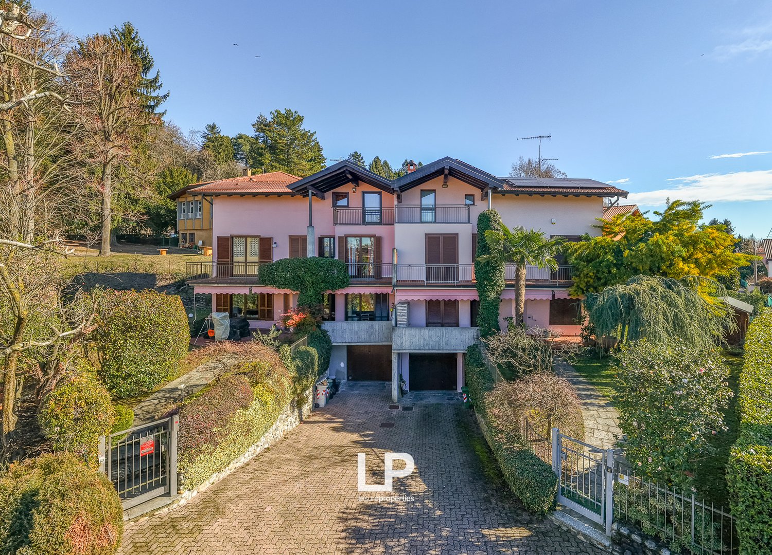 two-story house, pink exterior, brown roof, balconies, garage, raised ground floor