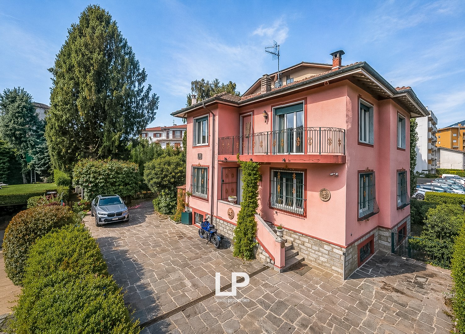 2 story house, pink exterior, brick ground floor, balcony, parking place, garden, trees
