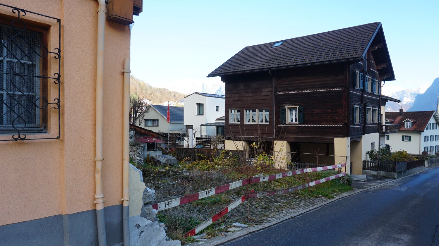 brown wooden house, gable roof, multiple windows, mountains in the background