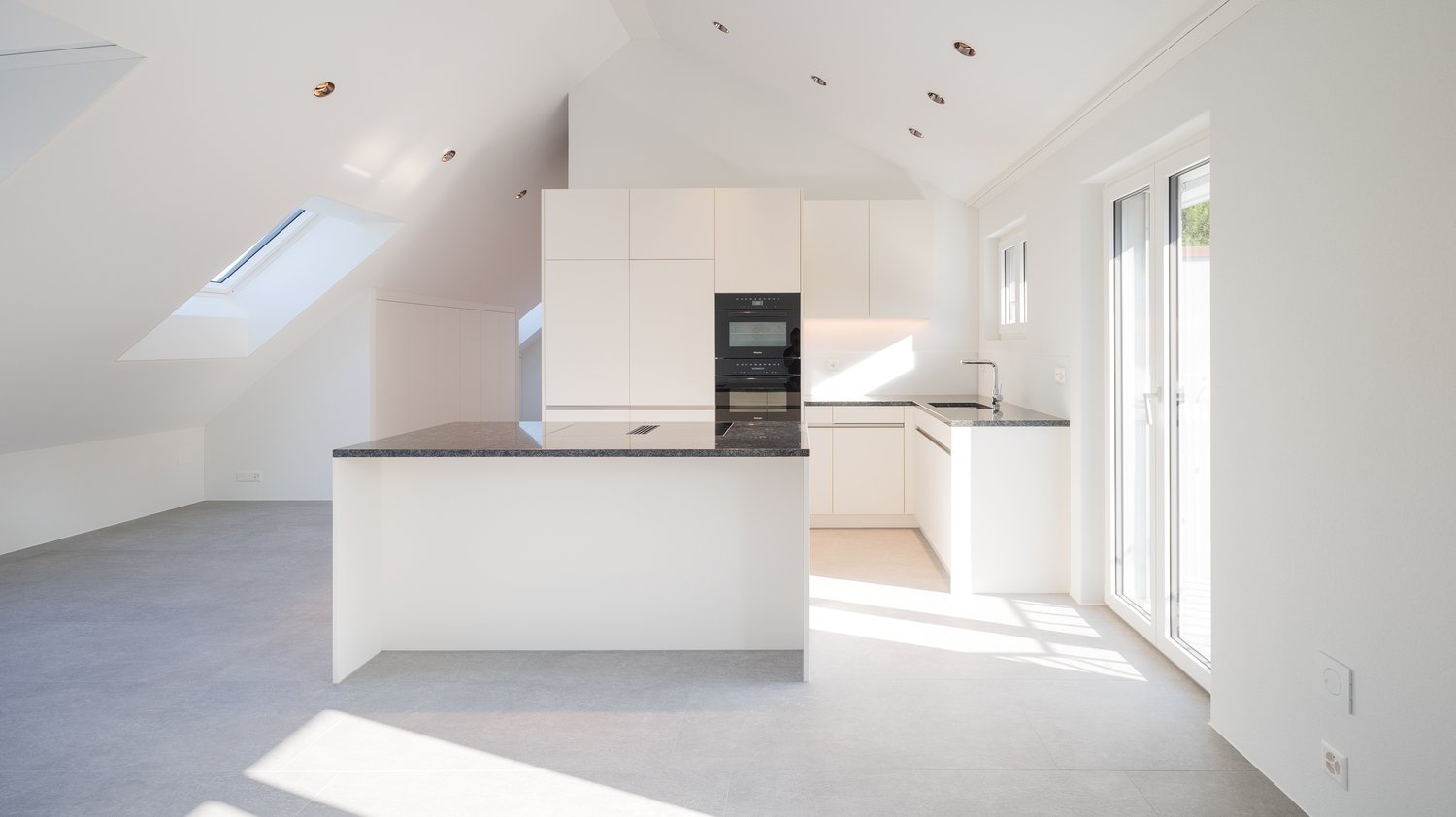 modern kitchen, island, white cabinets, black countertops, built-in oven and microwave, sink, skylights