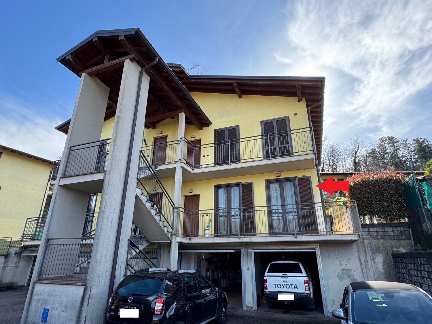 2-story yellow building with wooden roof, balconies, and a garage on the ground floor.