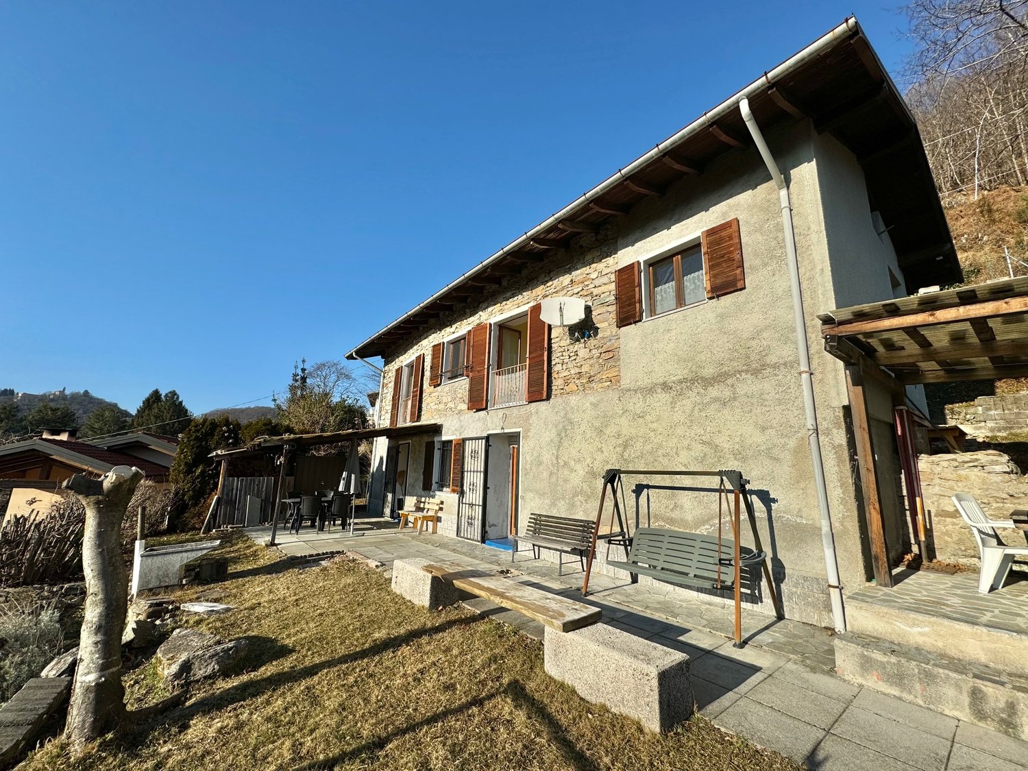 Raised ground floor house, stone walls, wooden windows, porch, garden, swing, benches