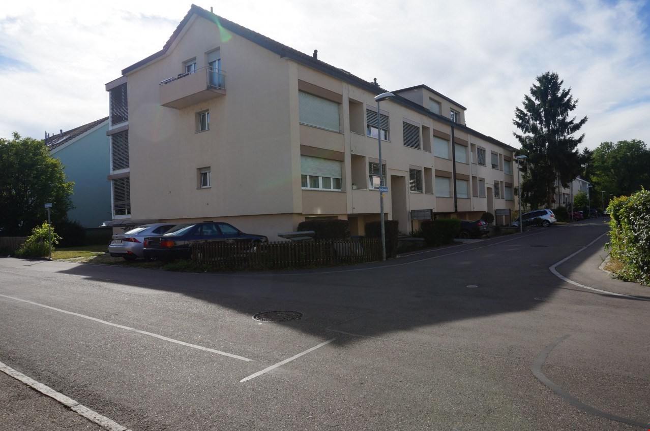 multi-family house, beige facade, balcony on the 2nd floor, street with parked cars