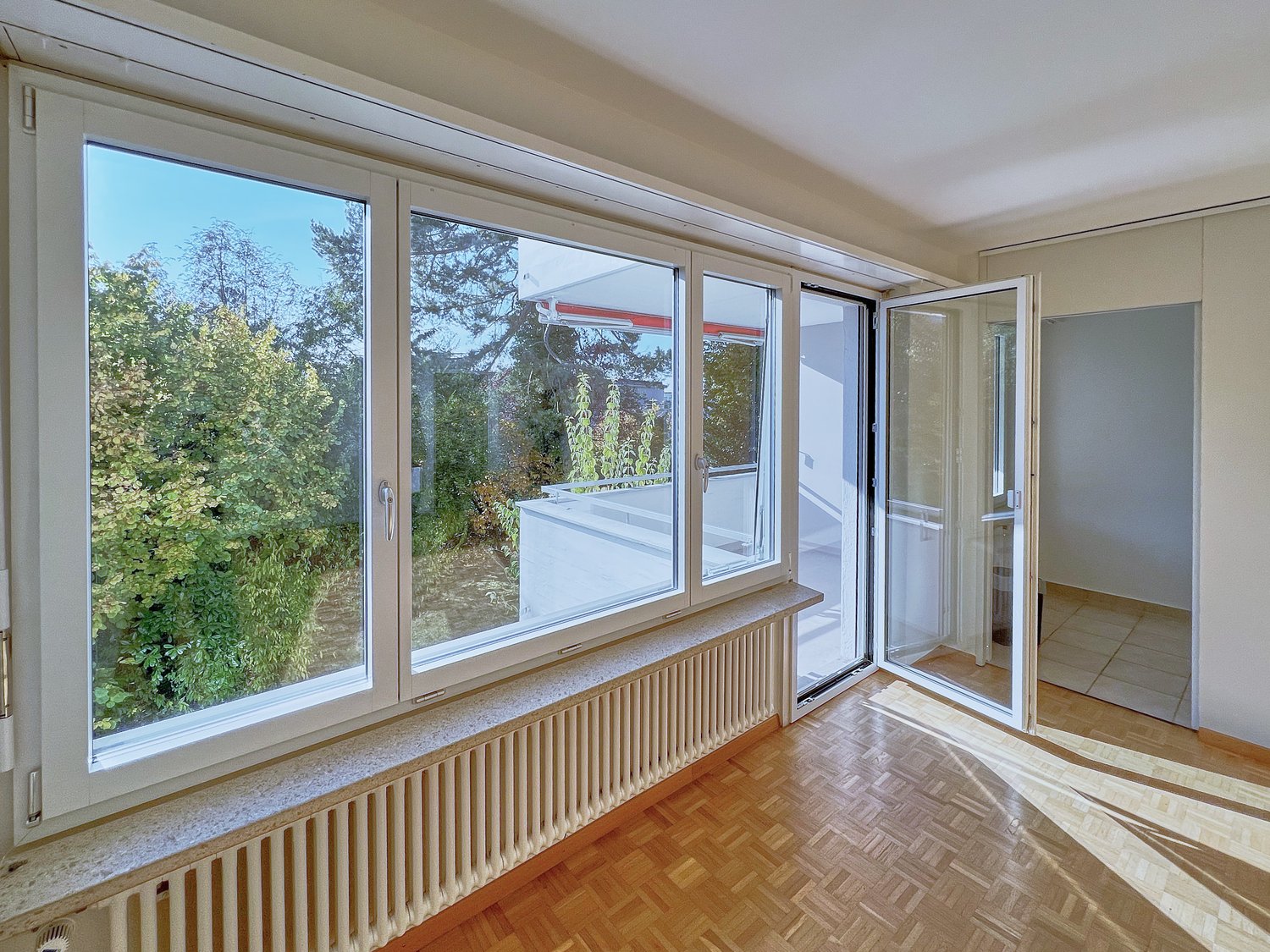 large windows, wooden floor, white walls, balcony, trees view
