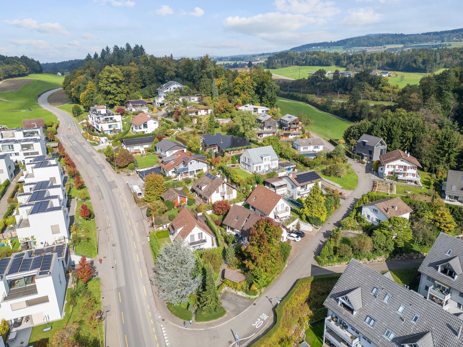 Residential area with single-family houses, solar panels on roofs, driveways, and driveways with speed limit signs