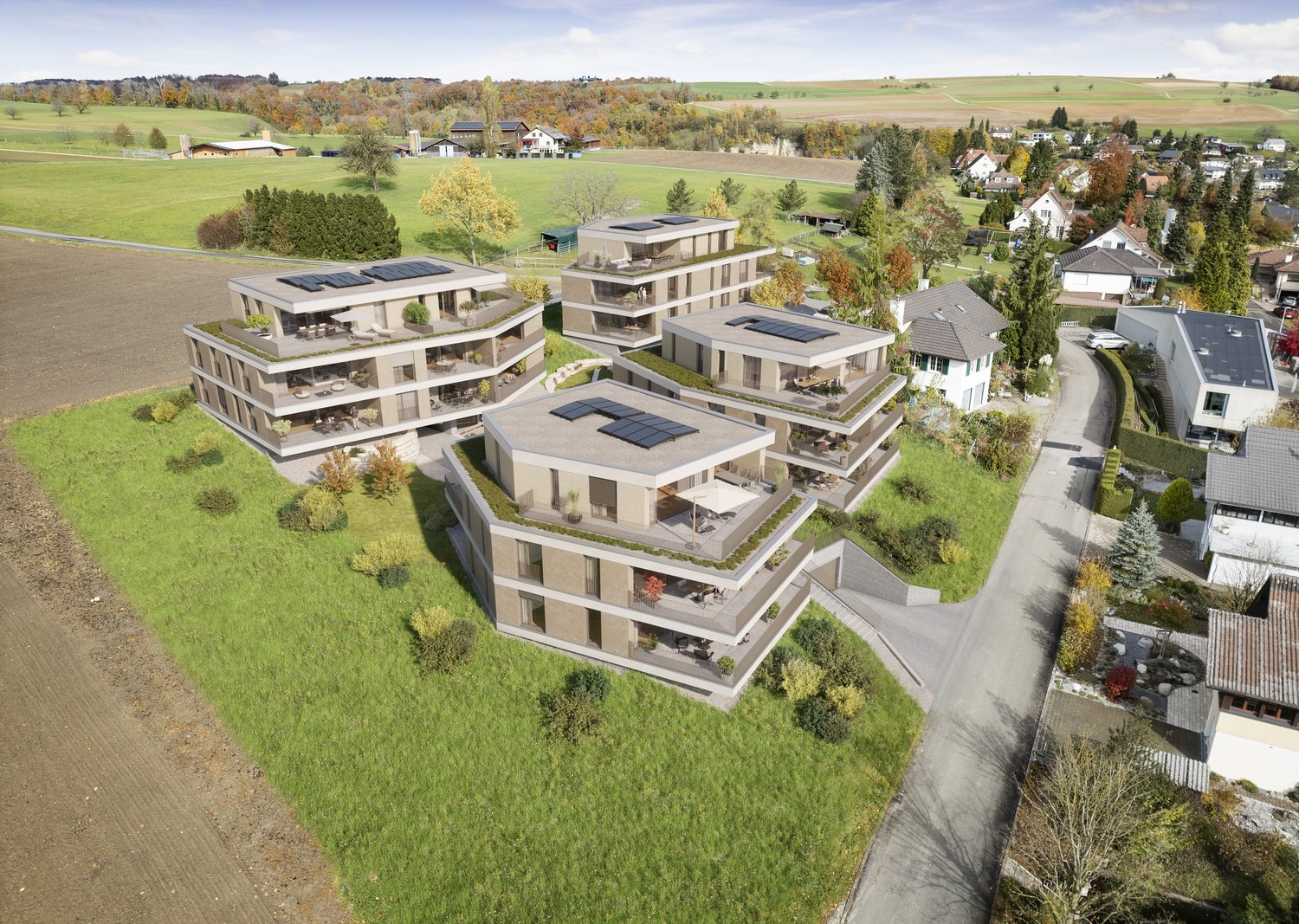 Multiple residential buildings, solar panels on roofs, landscaped gardens, wide open fields, surrounding trees, driveway