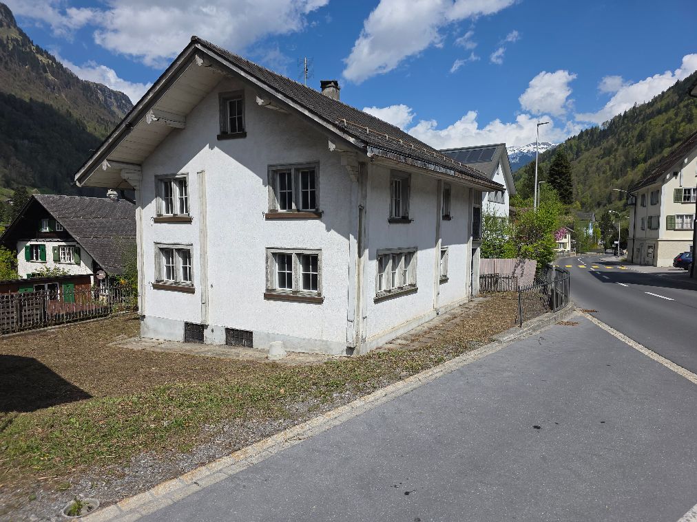 2 story house, white exterior, multiple windows, chimney, located on a street with mountains in the background
