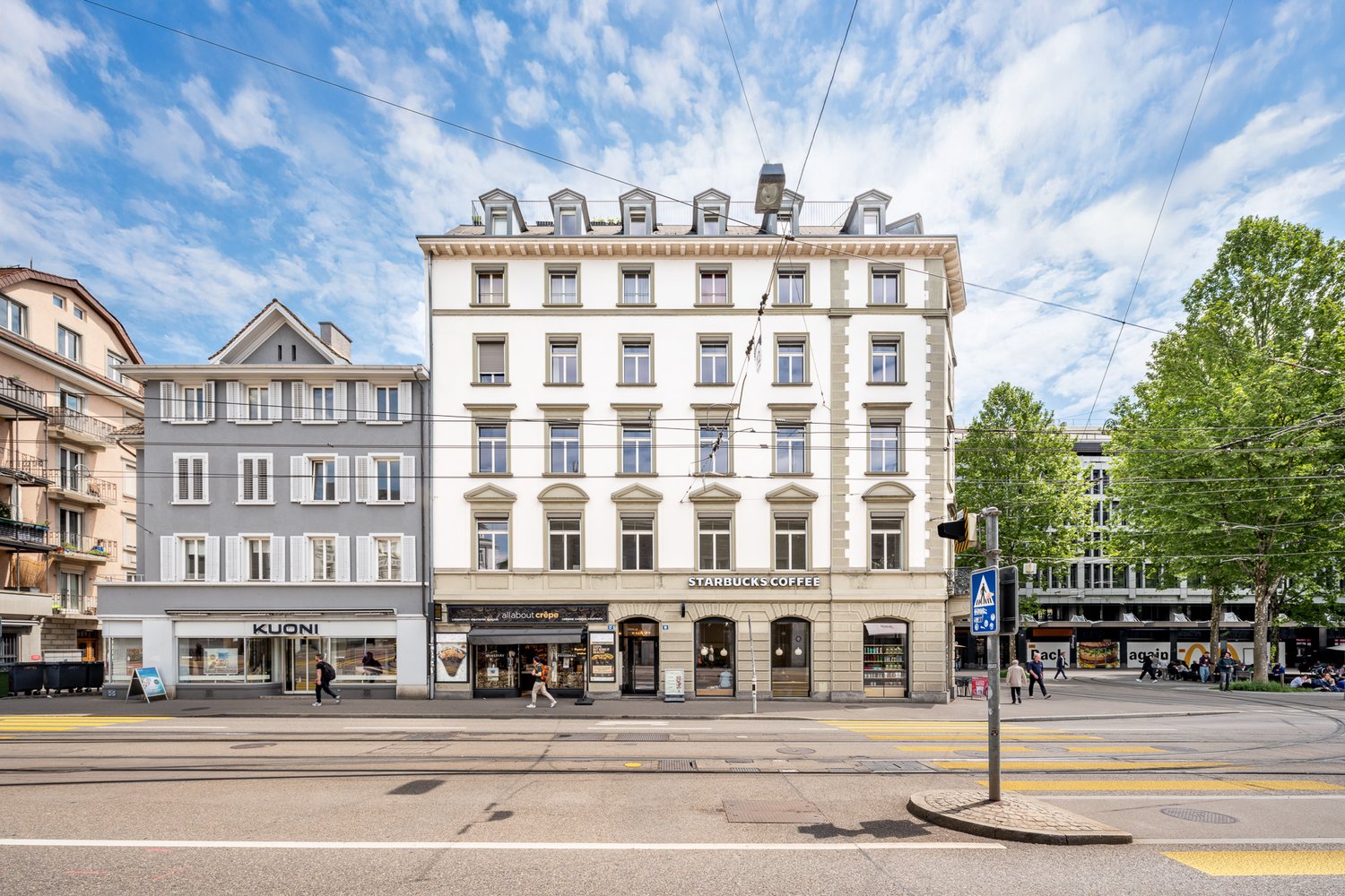 5 story white building with many windows, street level cafes