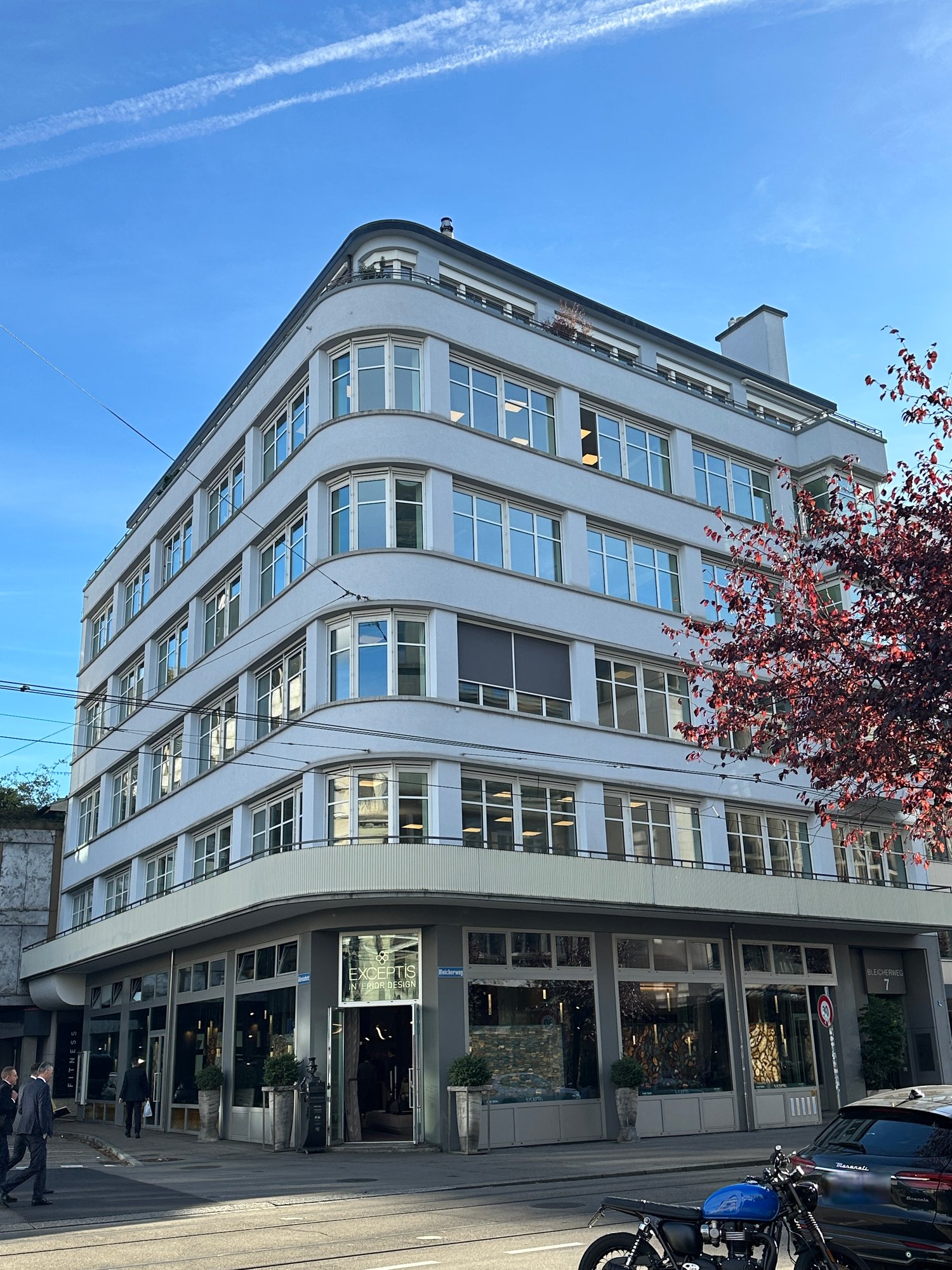 4 story white building, 24 windows, modern architecture, entrance glass door, 4 plants in front, entrance on the ground floor