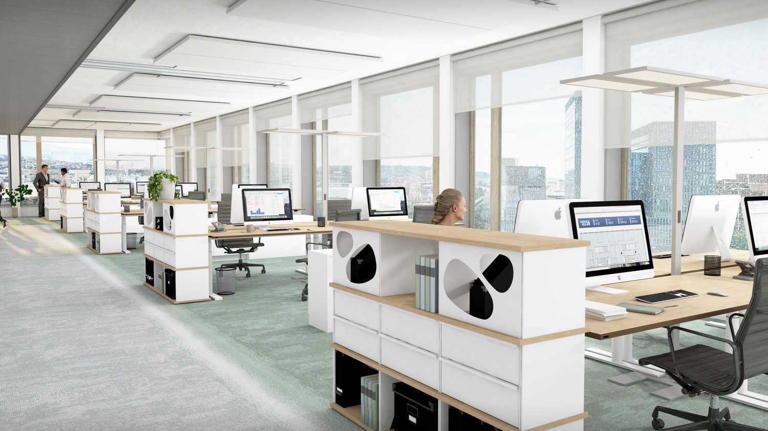 An open-plan office with glass windows, modern desks, and a view of the city outside. There are computers, monitors, and plants. Two people are standing and conversing. The floor is tiled.