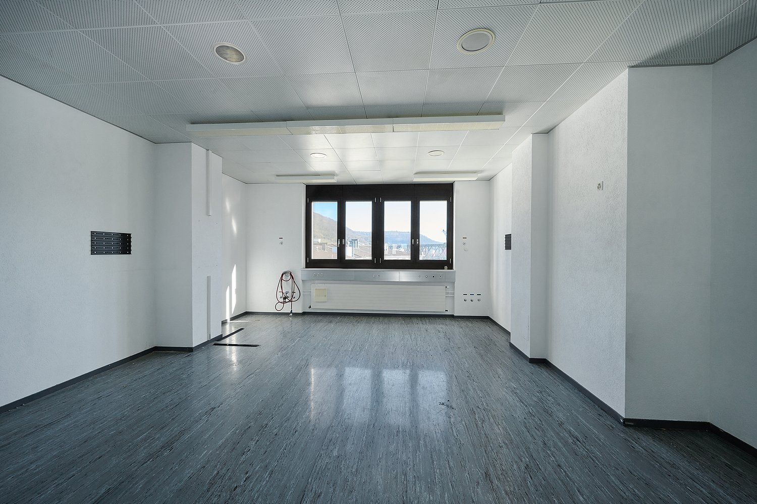 empty room, white walls, gray floor, large window, radiator