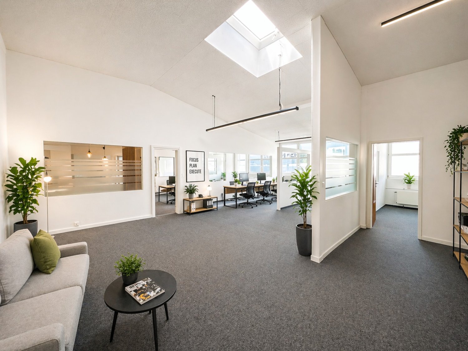 modern office space, white walls, gray carpet, skylight, office desks, plants, gray couch, black coffee table