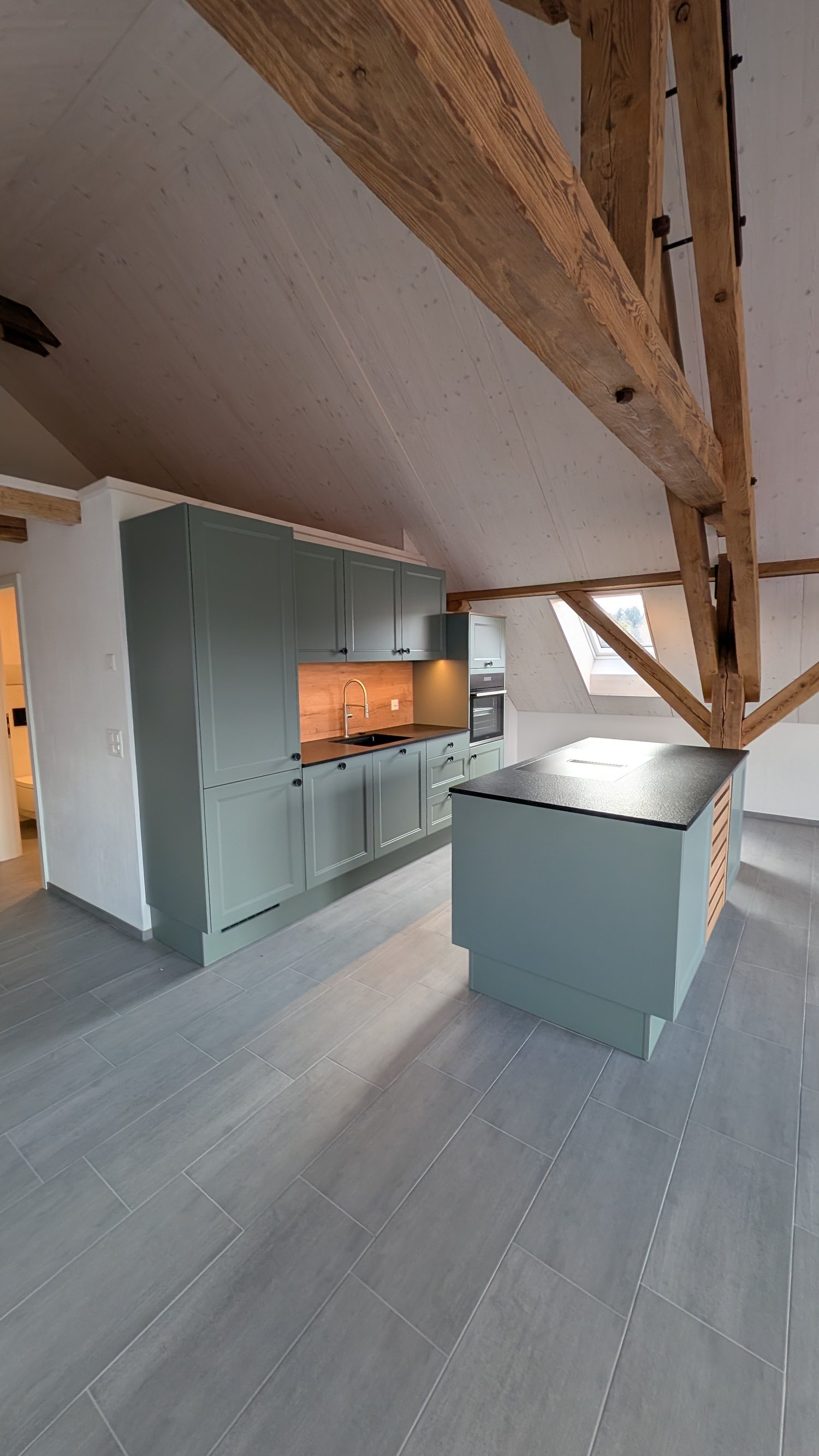 modern kitchen with wooden beams, gray cabinets, black countertop, island, sink, faucet, oven, dishwasher