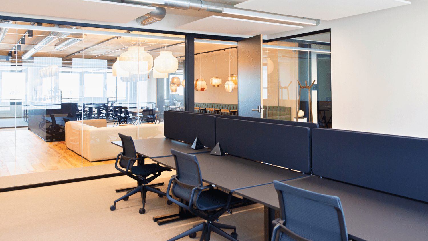 Open office with multiple cubicles, desk, chairs, glass partition walls, lamps, carpet