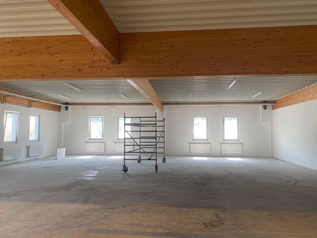 spacious room, wooden beams, white walls, metal roof, several windows, large steel scaffolding